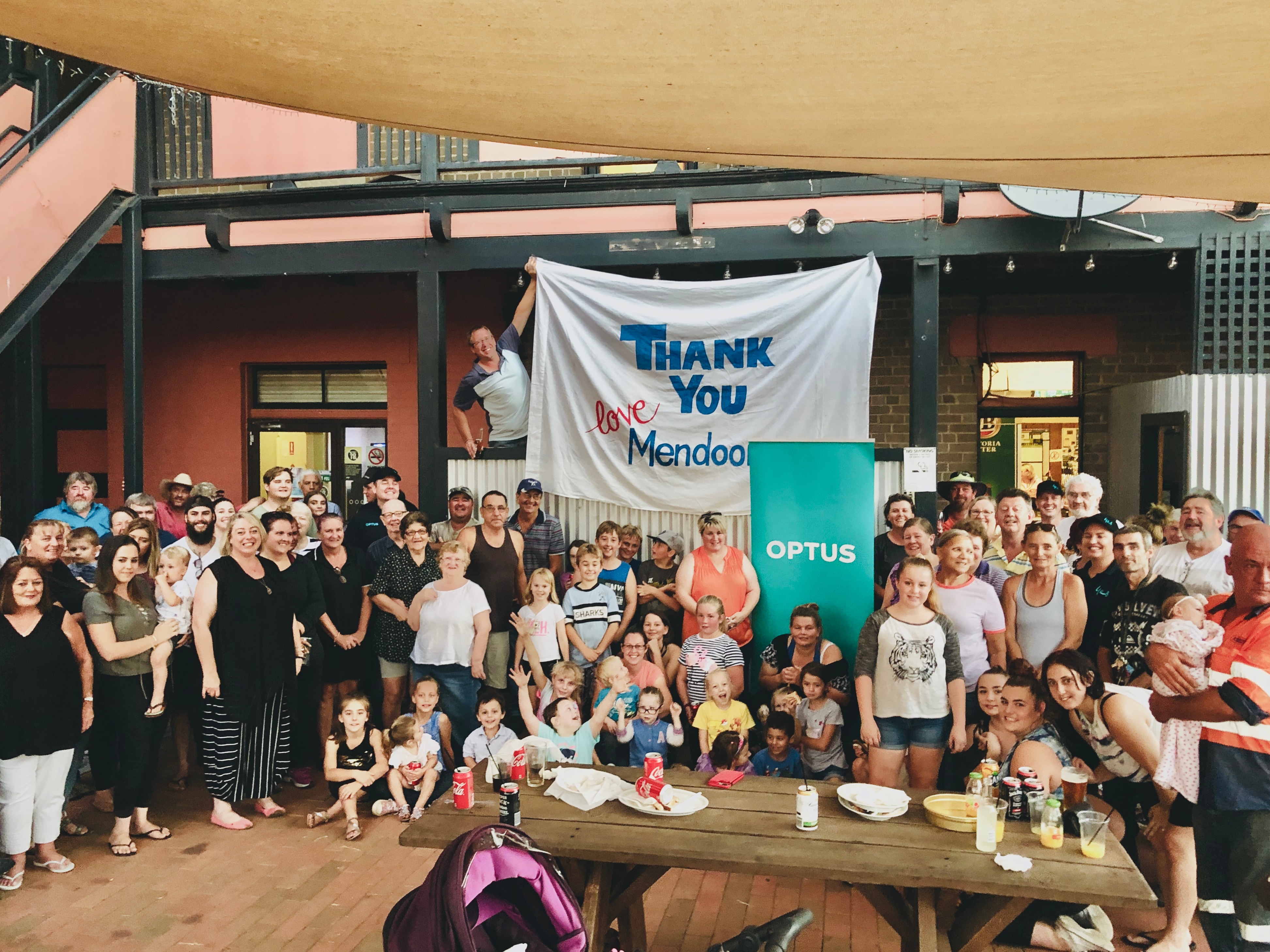 Group photo of Mendooran Community with sign in the backgroun that reads: Thank you love Mendooran