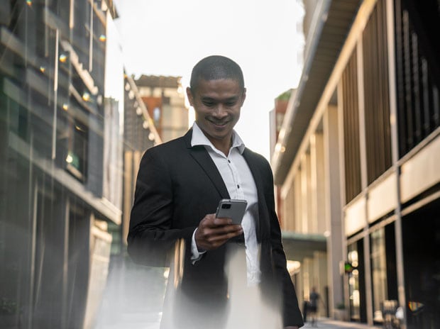 Smiling man in business suit looking at phone with an urban backdrop