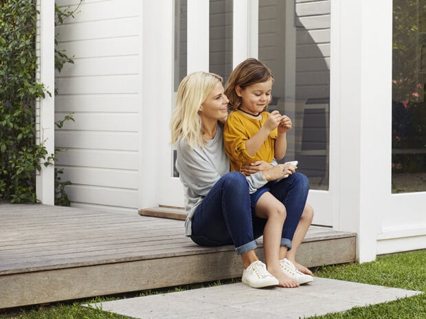 Mother with child sitting on her lap on the porch of a house