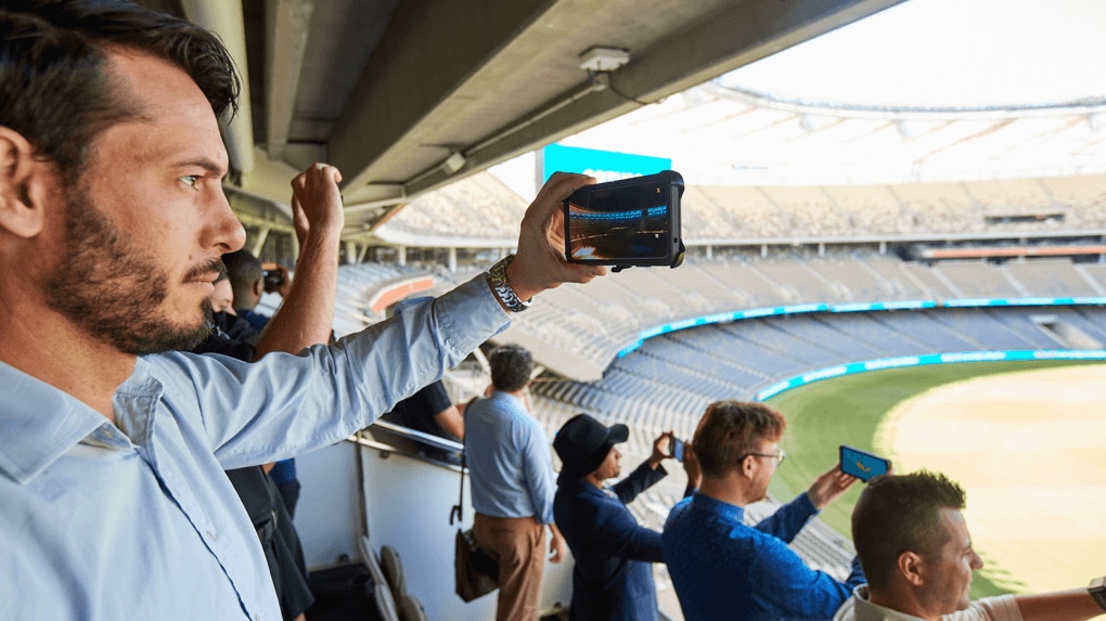 Man using his phone to film in a sports stadium