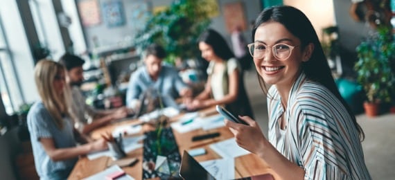 Lady with glasses smiling whilst holding phone