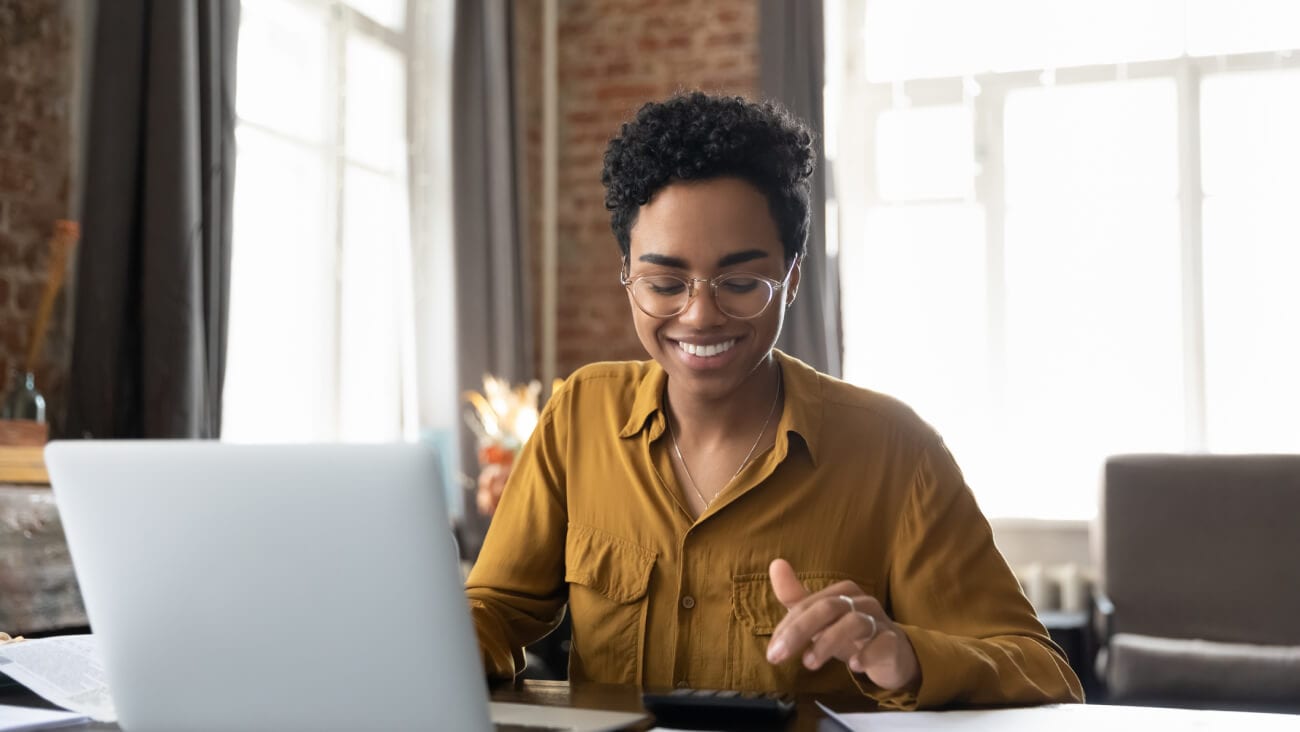 Smiling business woman in a yellow shirt with a laptop.