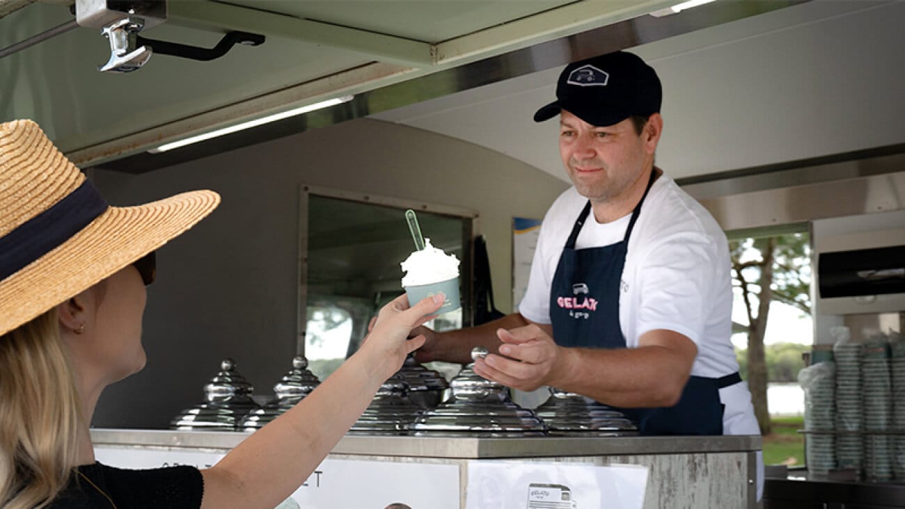 Woman in a straw hat buying an ice-cream from an ice-cream van.