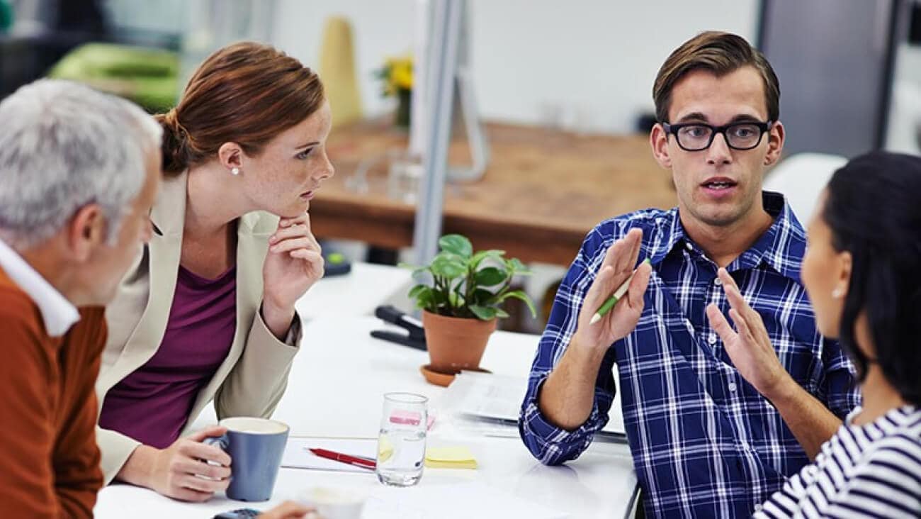 Several businesspeople around a table discussing the importance of a personal brand for business leaders.