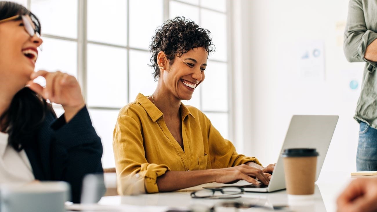 Smiling woman with short hair, sitting with a laptop in a business meeting. 