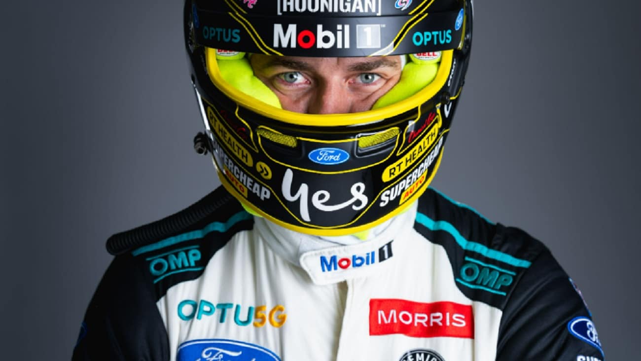 Chaz Mostert, Supercar driver in driving gear including helmet with Optus logo.