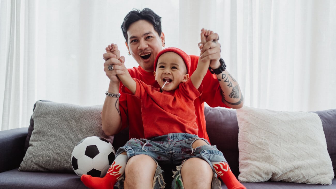father and son cheering while watching a football match