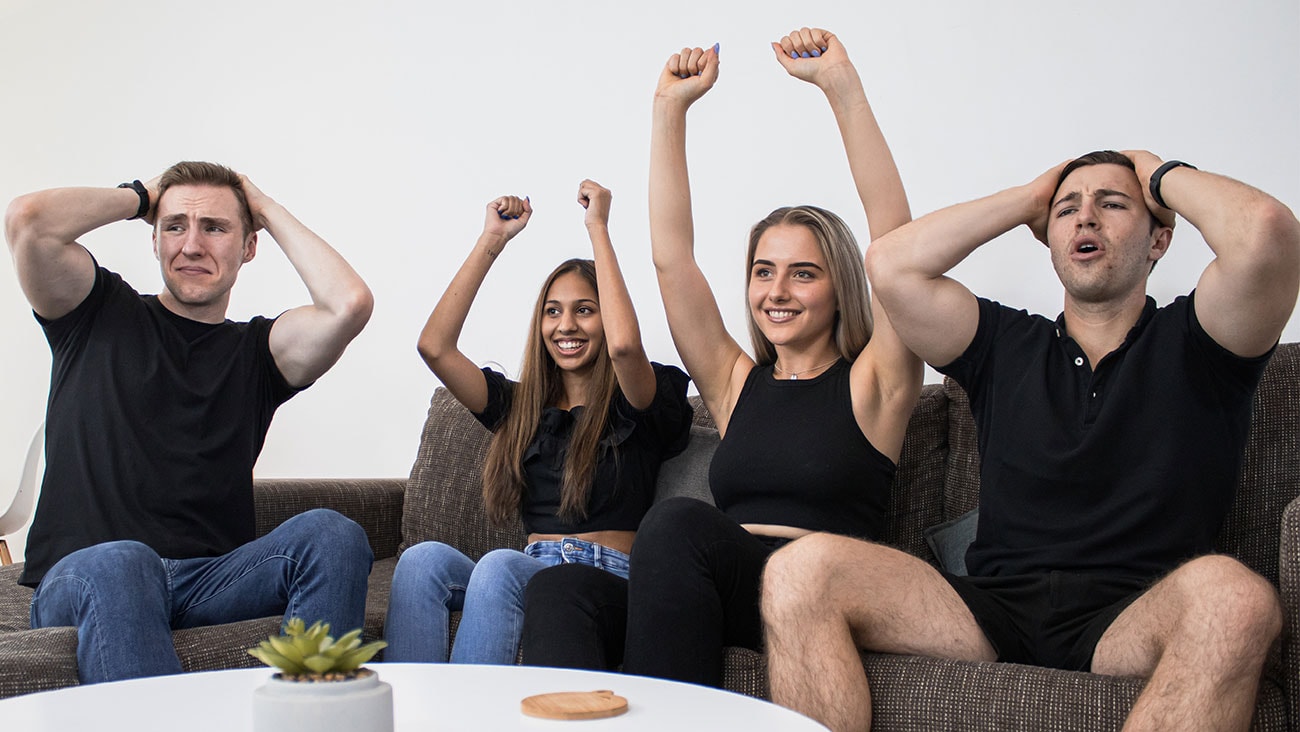 Young women and men laughing and watching tv