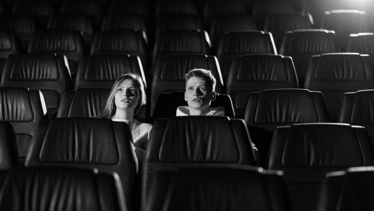 Black and white image of two people sitting in the cinema