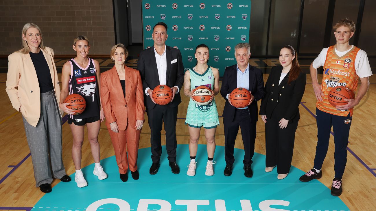 A group of seven people standing on a basketball court in front of the Optus logo