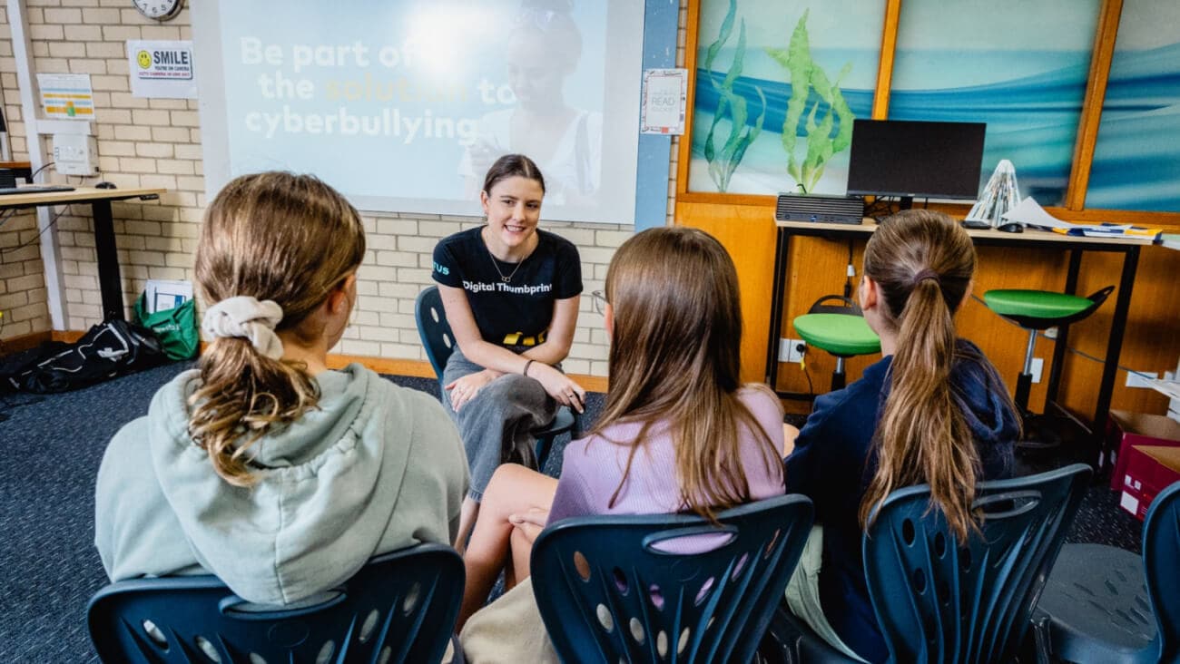 A facilitator sitting with students in an Optus Digital Thumbprint workshop.