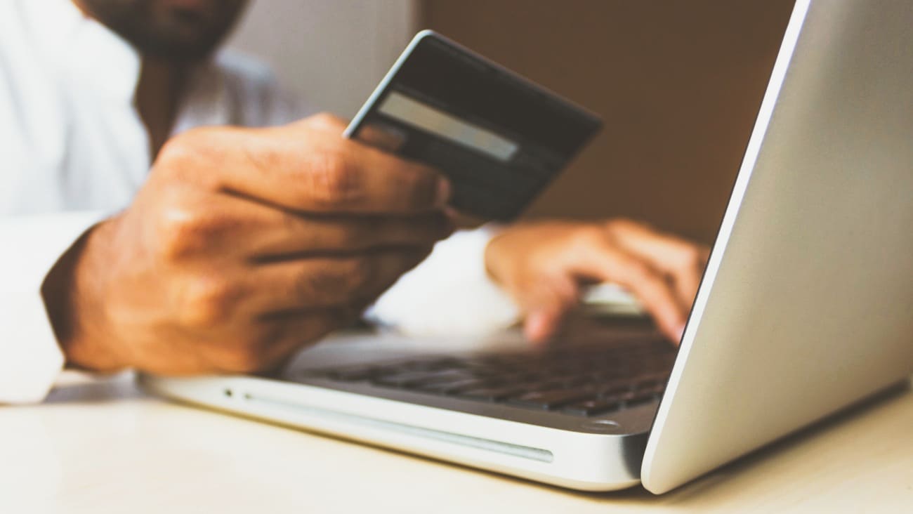 Person holding credit card using laptop