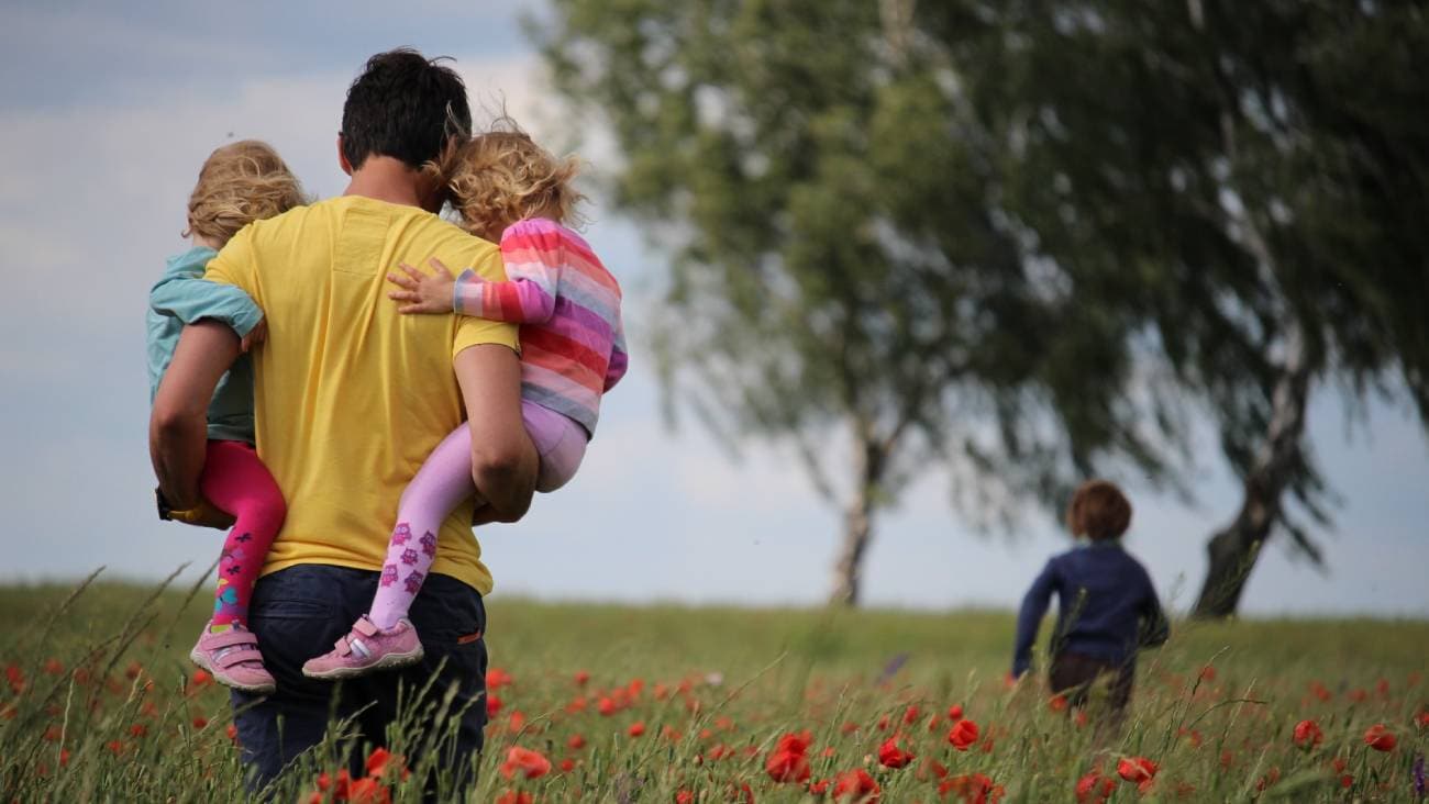 Father and three children in a field with red poppies.