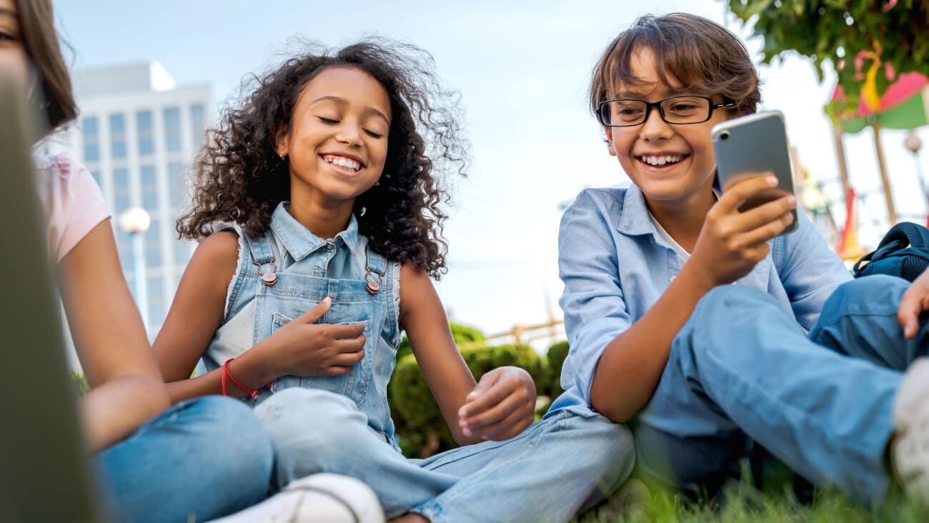 Young girl and boy smiling with a mobile phone