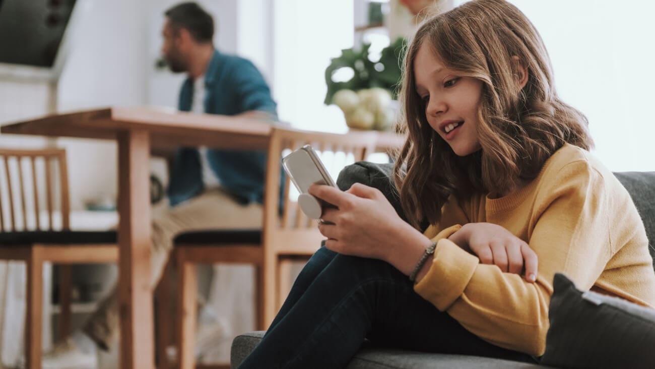 Young girl using a mobile phone while sitting on the floor in the family dining room