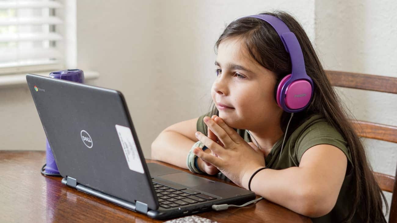 Young girl with headphones watching a laptop screen