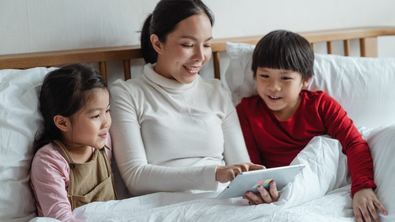 Family in bed all looking at a tablet
