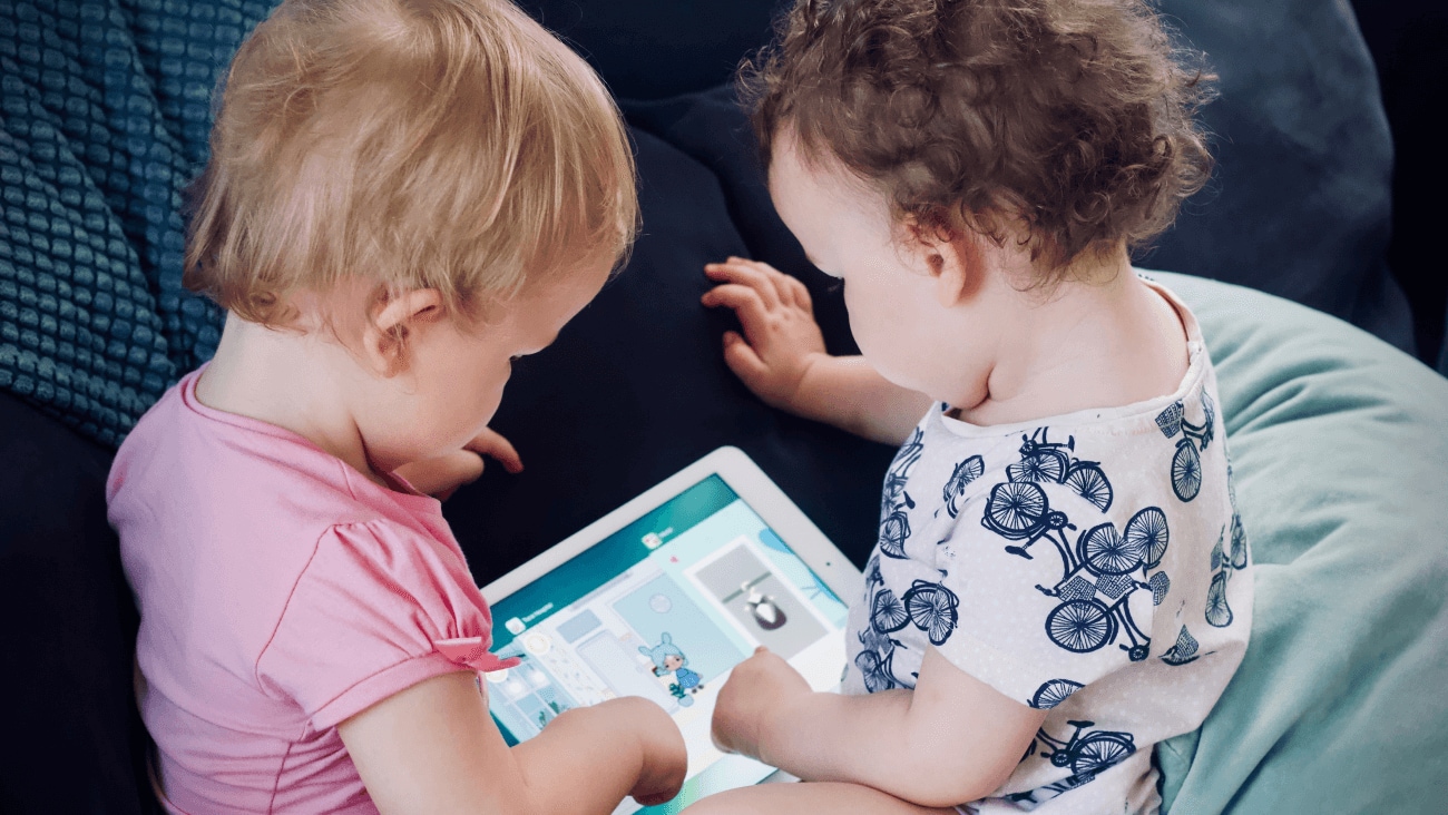 Two toddlers playing with a tablet
