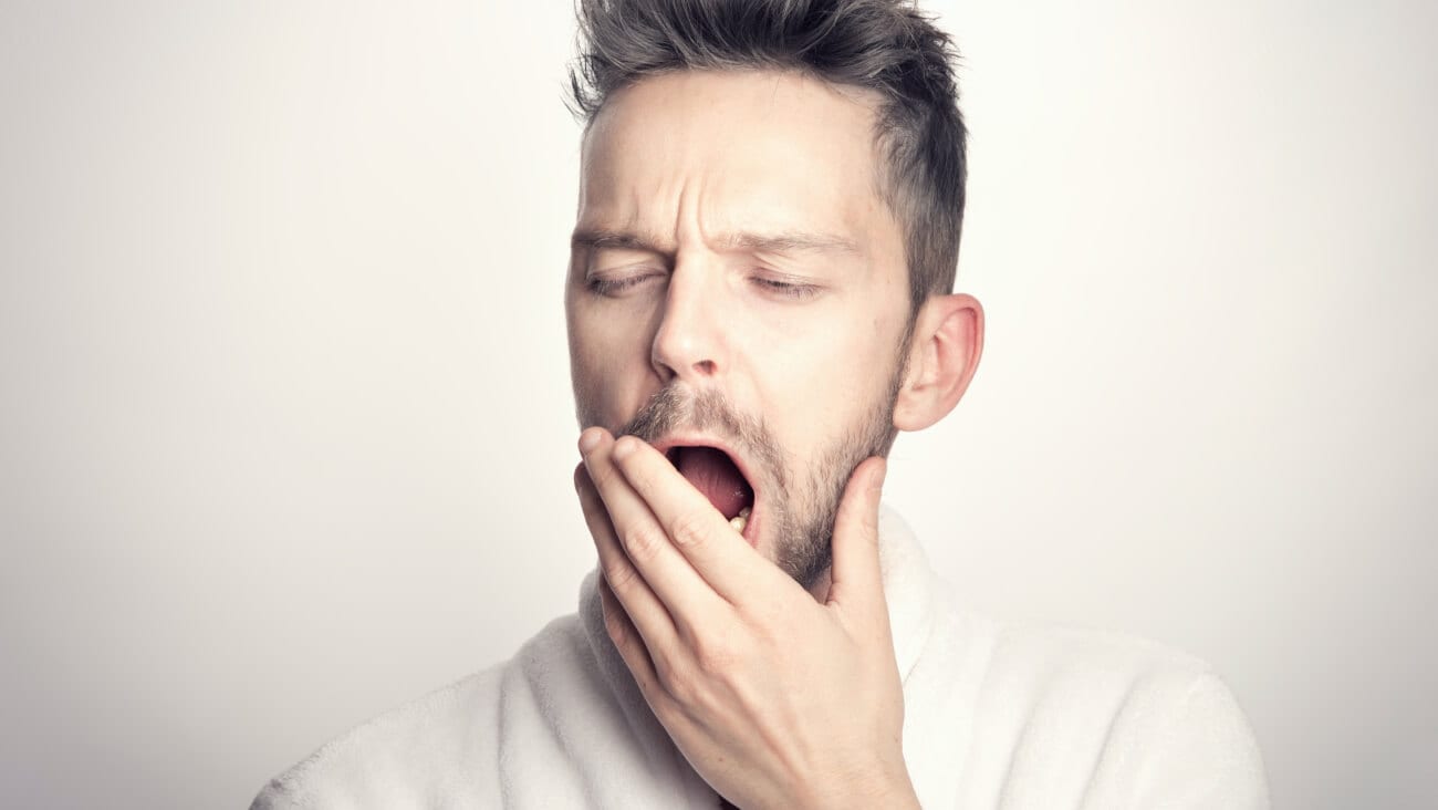 man yawning and covering his mouth with his hand