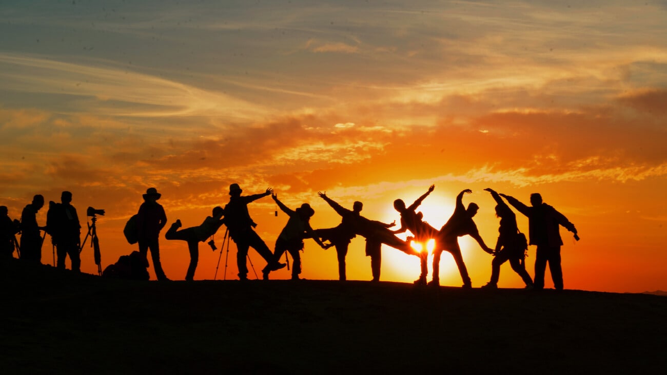 silhouette of a group of friends behind a sunset