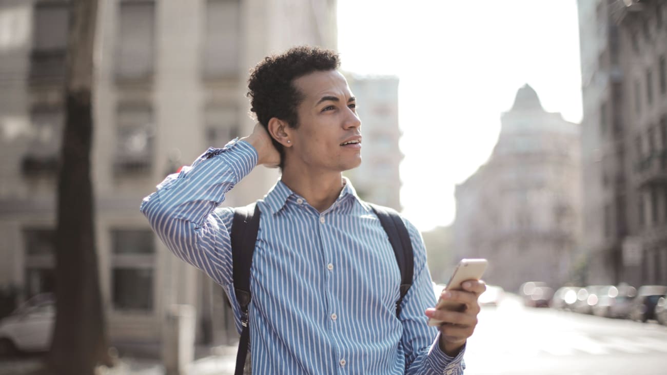 Tourist looking lost in a foreign city while holding a smartphone.