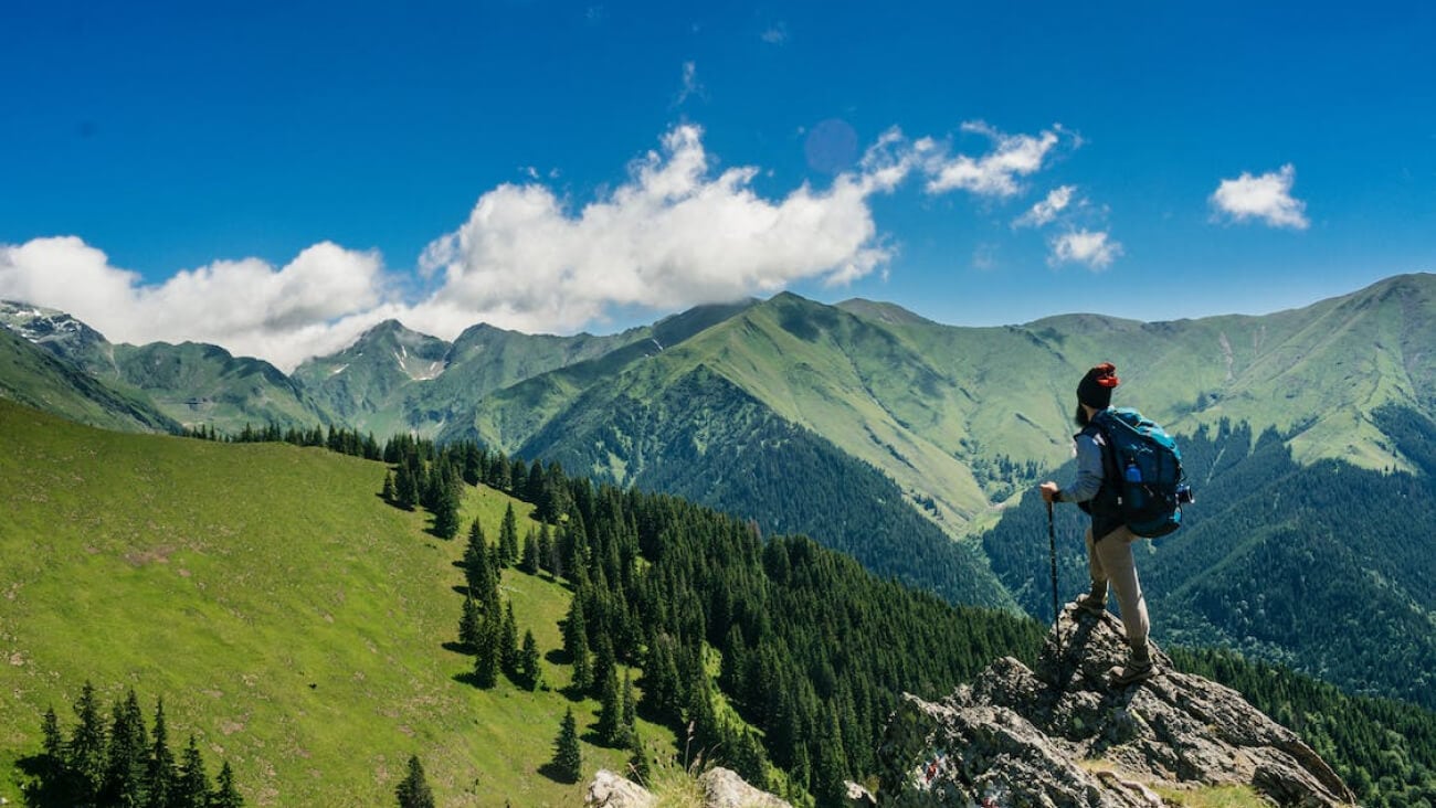 Man standing on cliff peak overlooking a mountain
