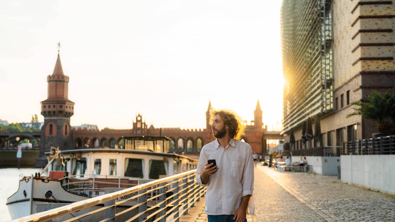Young many walking with his mobile phone by the river in Berlin.