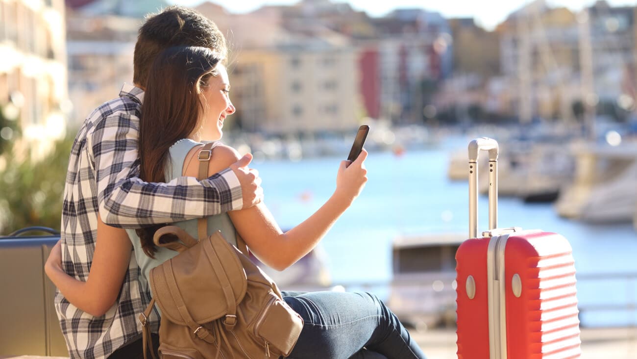 happy couple looking at phone while on holiday