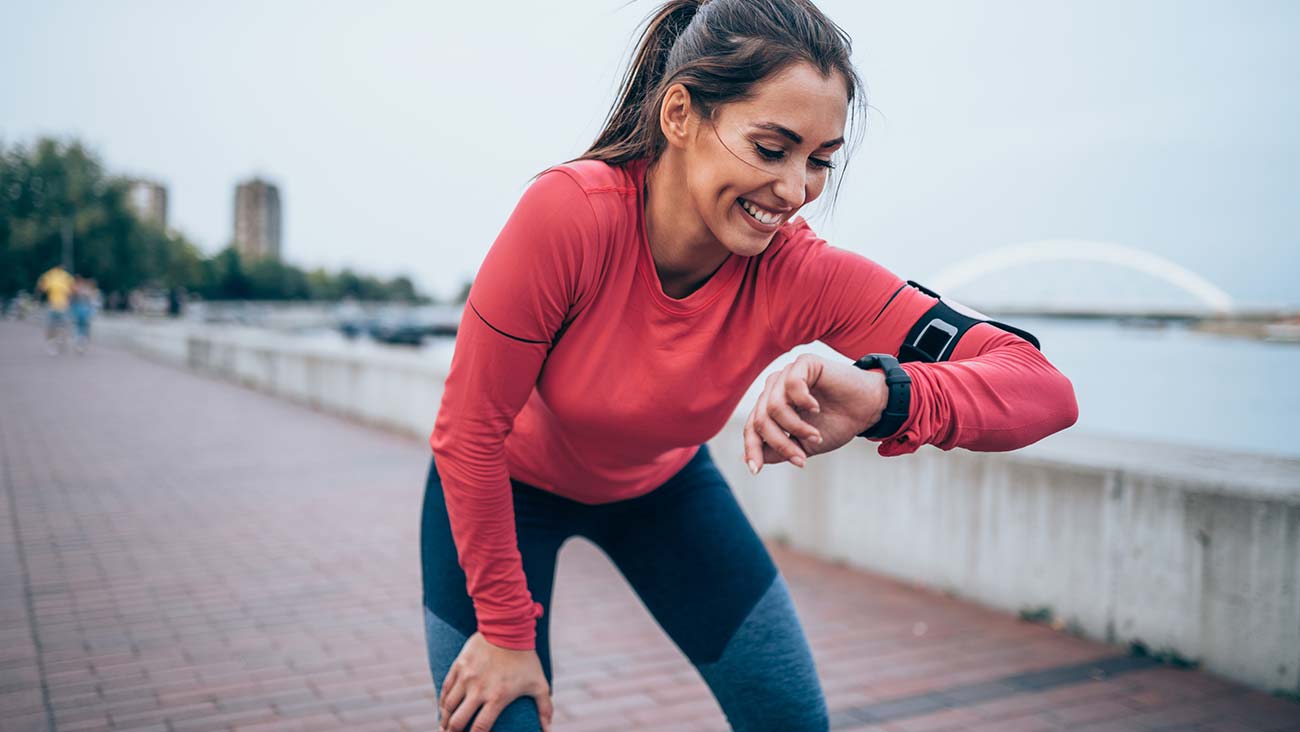 Young woman out jogging is looking at her smart watch