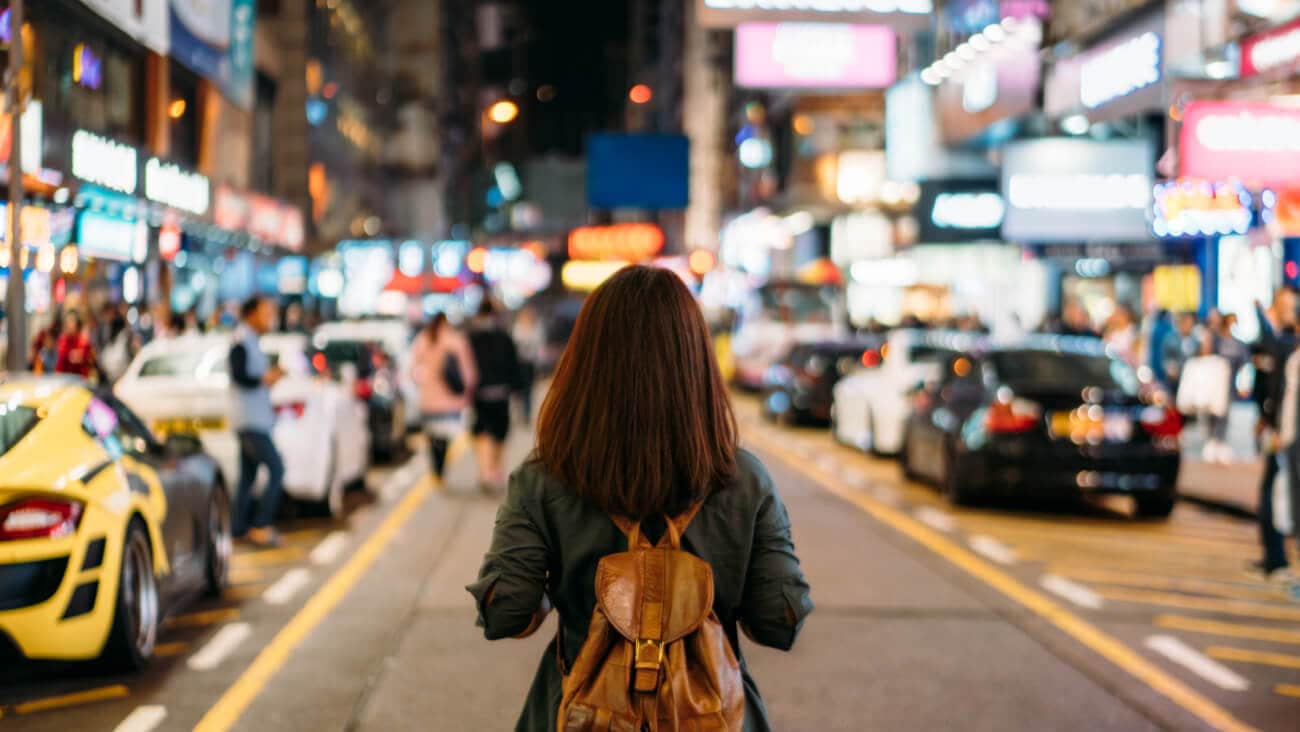 young woman traveler traveling into Mongkok street market at night in Hong Kong
