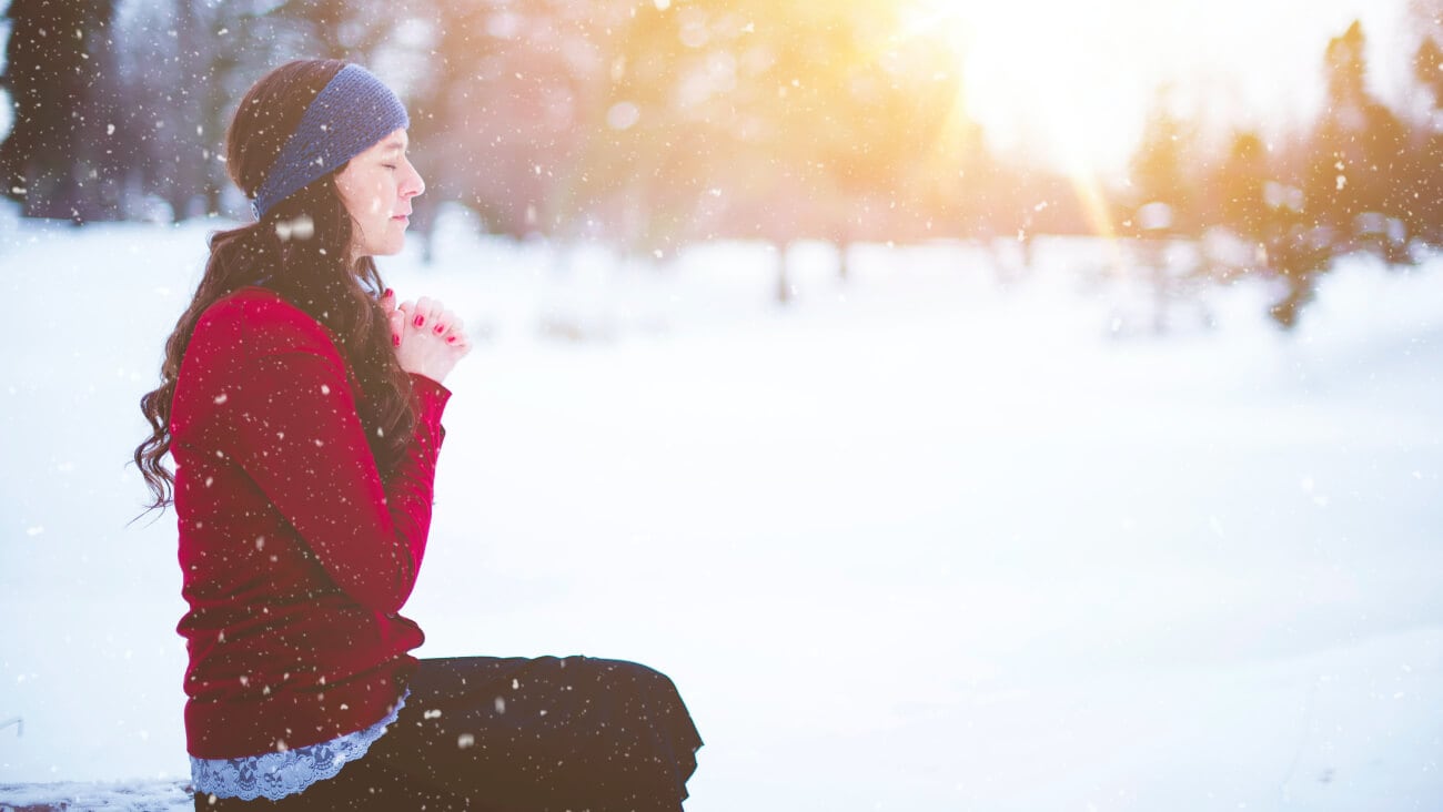 woman doing yoga with closed eyes surrounded by snow