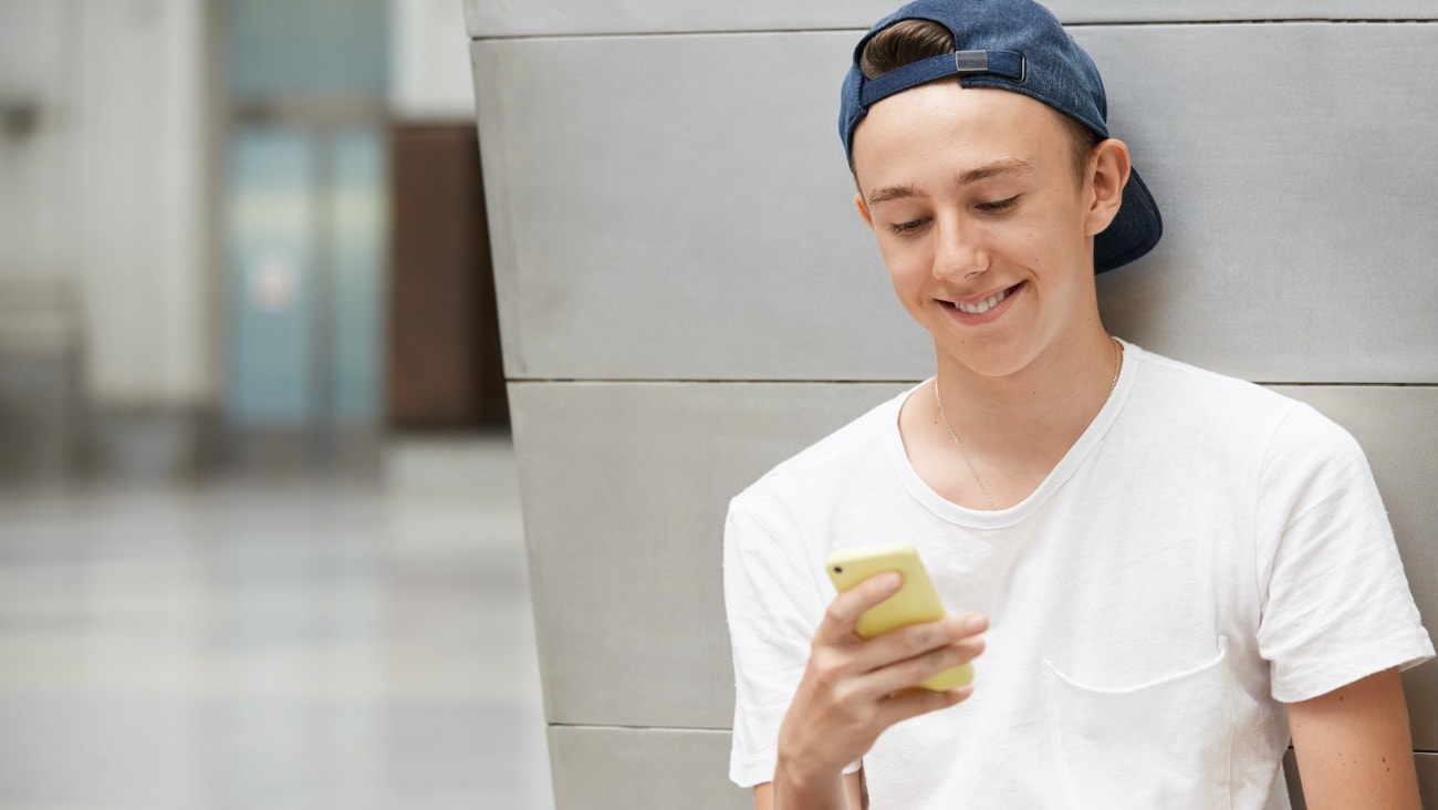 A young boy holding a phone and smiling