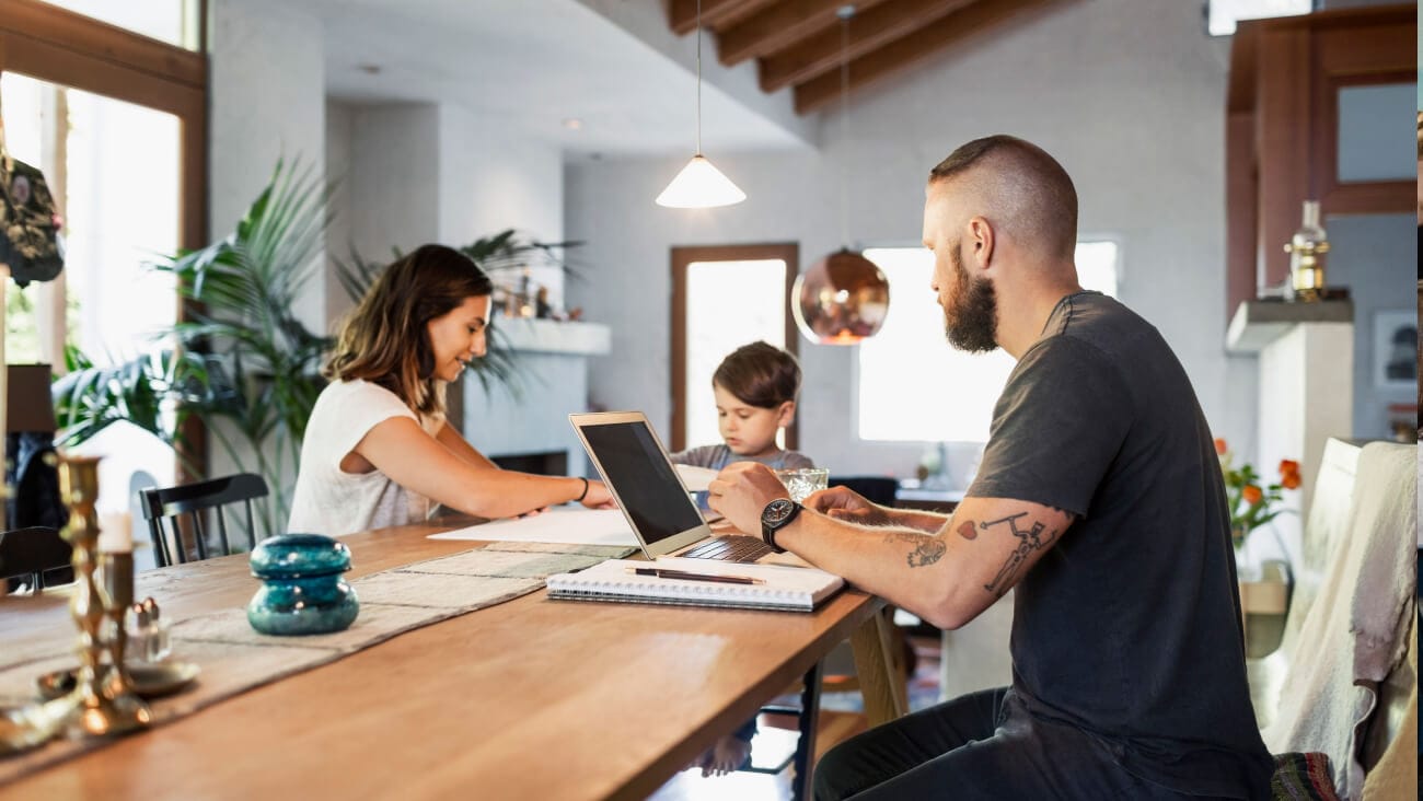 Young family sitting around the kitchen bench with a laptop.