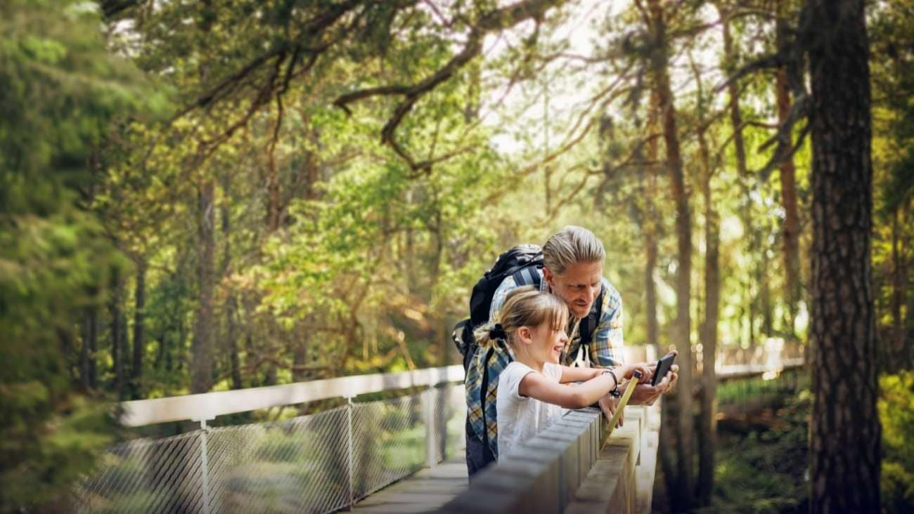 A father and daughter on a bridge holding a phone