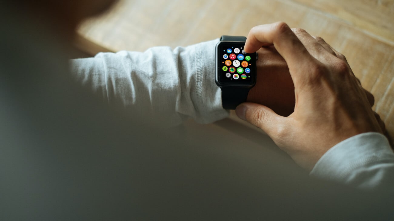Man wearing a white shirt using a smartwatch