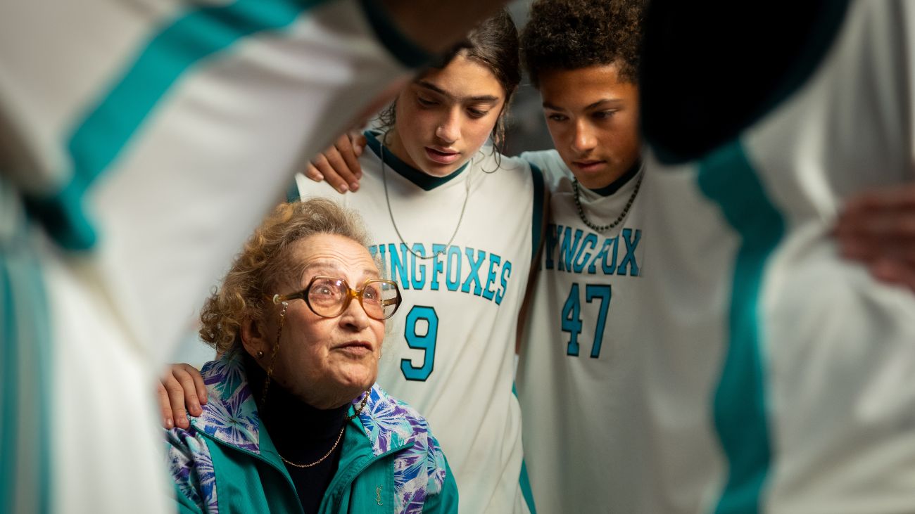 A charismatic elderly woman coaching a team of young basketball players