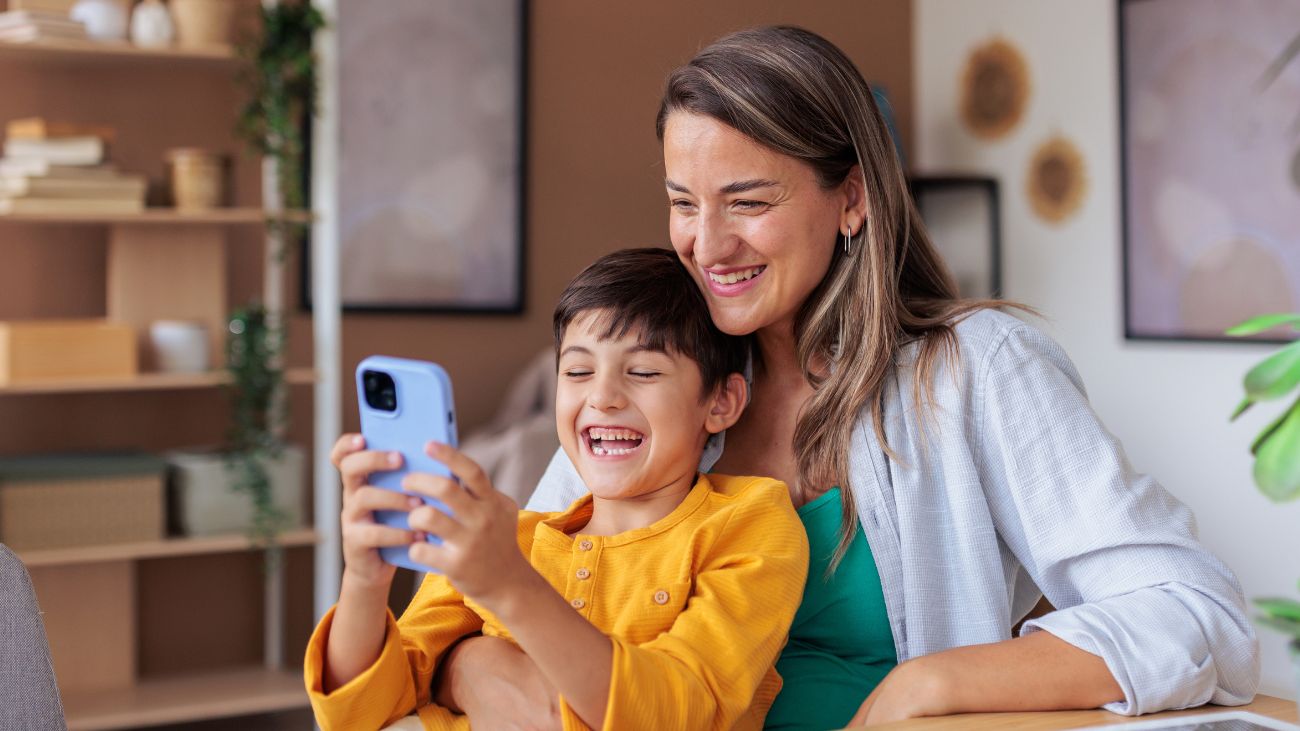 A mother and child looking happy at a phone