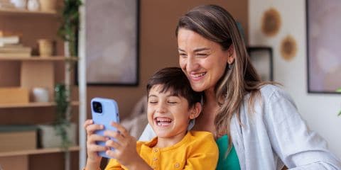 A mother and child looking happy at a phone