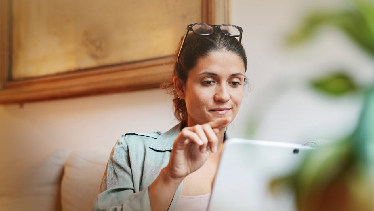 A young woman holding a tablet and looking at the tablet screen.