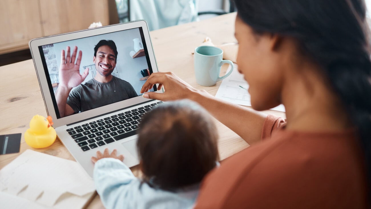 Young mother with baby communicating with the father via a laptop