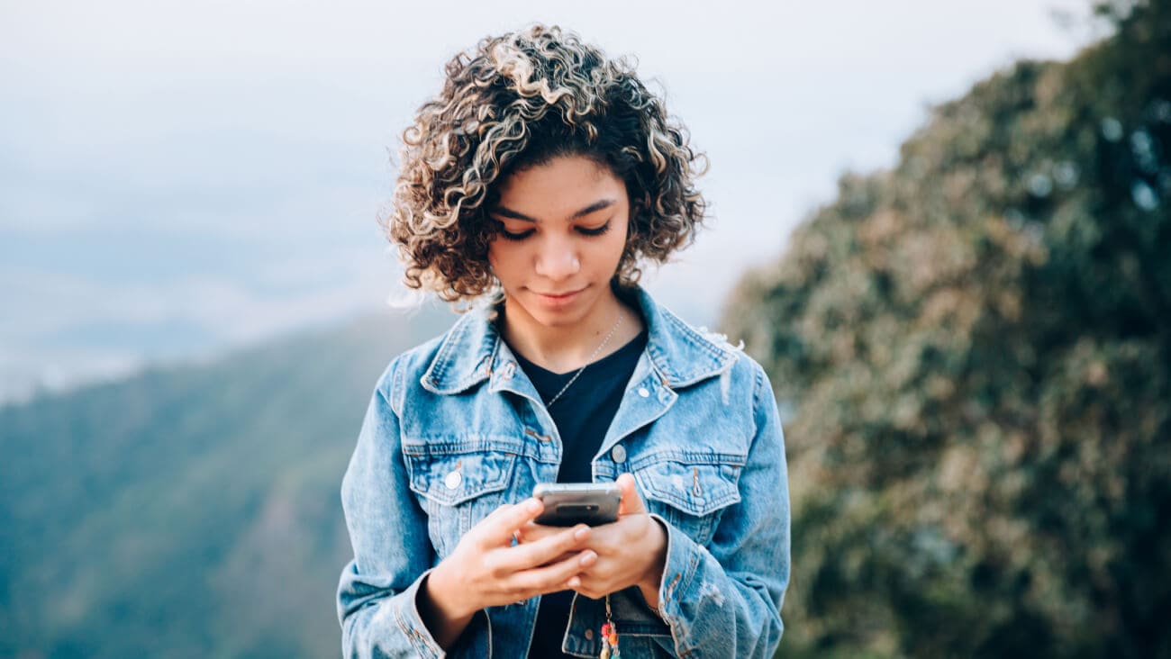 Young teenager in a denim jacket using a mobile phone
