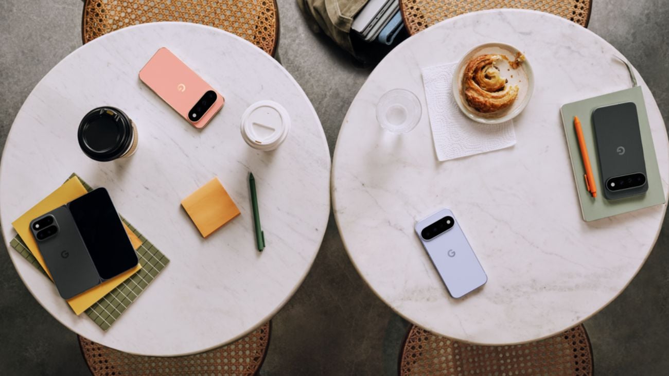 Several Google Pixel 11 phones on two white tables surrounded by books, writing implements and food