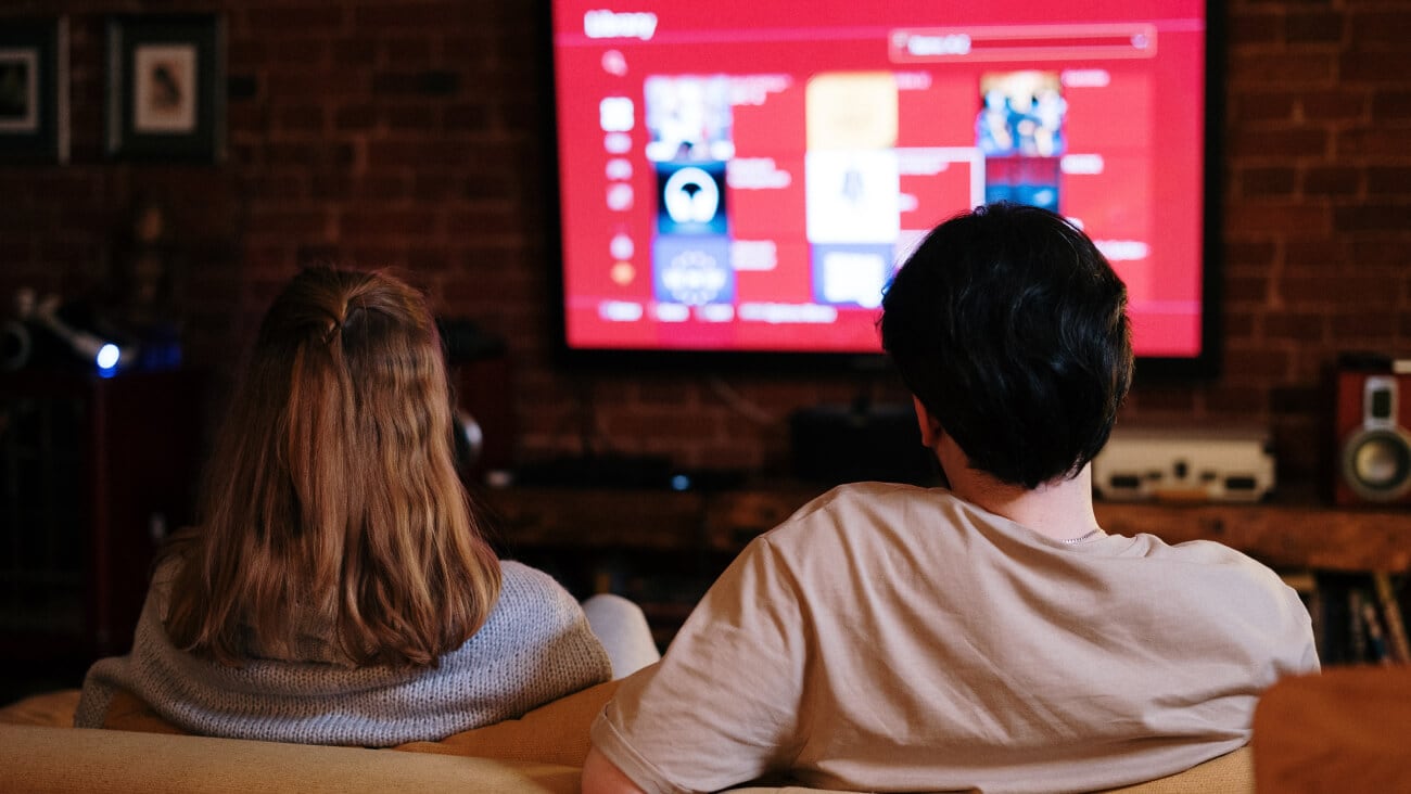 woman and man sitting on a coach watching streaming on tv.