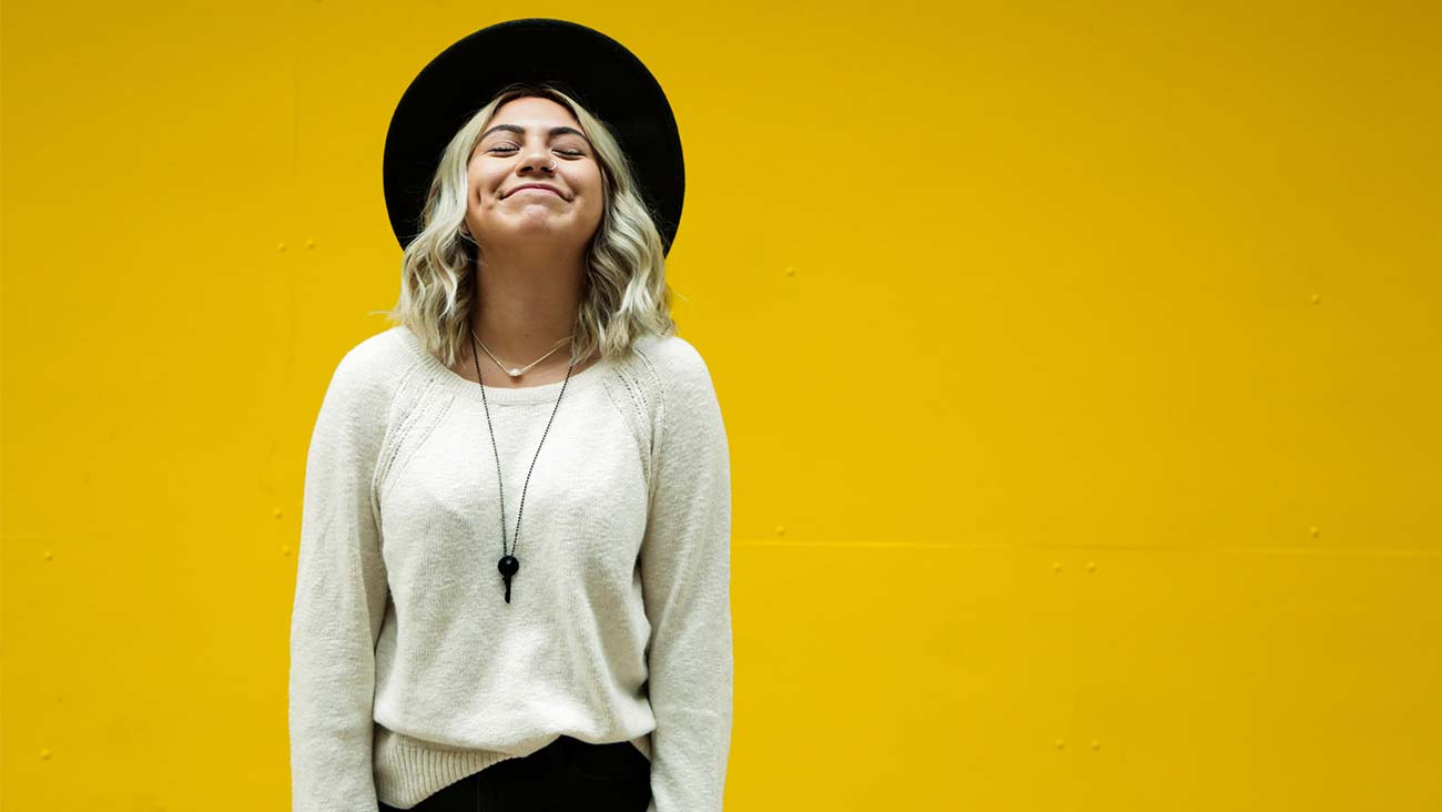 Young happy woman standing in front of a yellow background