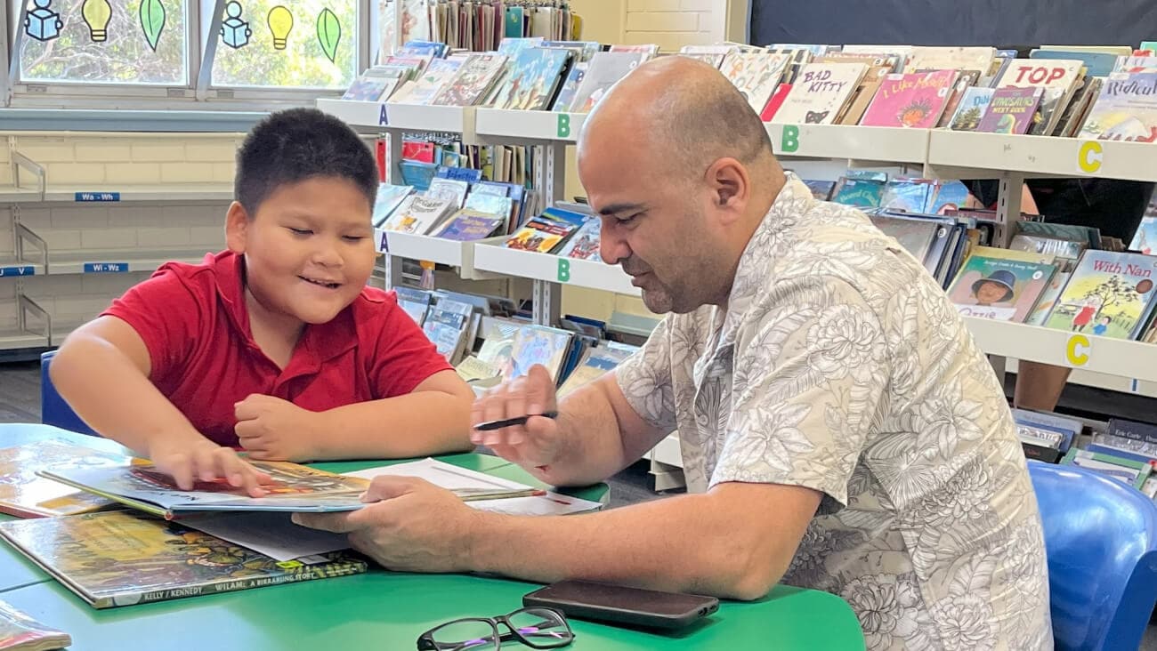 Young school boy in classroom being assisted by Optus volunteer