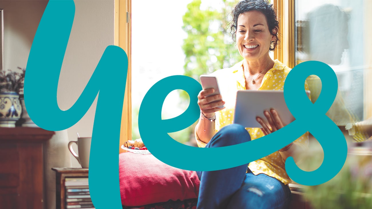 A smiling woman holding a tablet and mobile phone