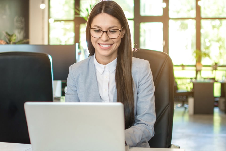 A smiling lady looking at her laptop screen.