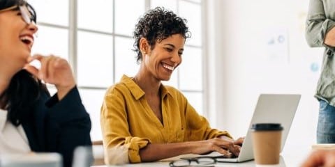 Smiling woman with short hair, sitting with a laptop in a business meeting. 