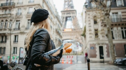 Girl in a beret carrying a baguette looking at the Eiffel Tower