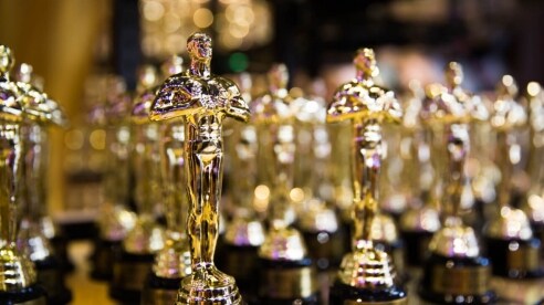 Many Academy Awards statuettes lined up on a table